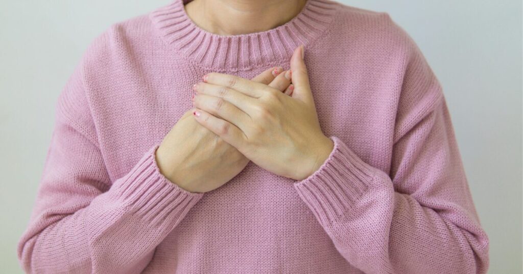 胸に手を当てて、気持ちを整えている女性