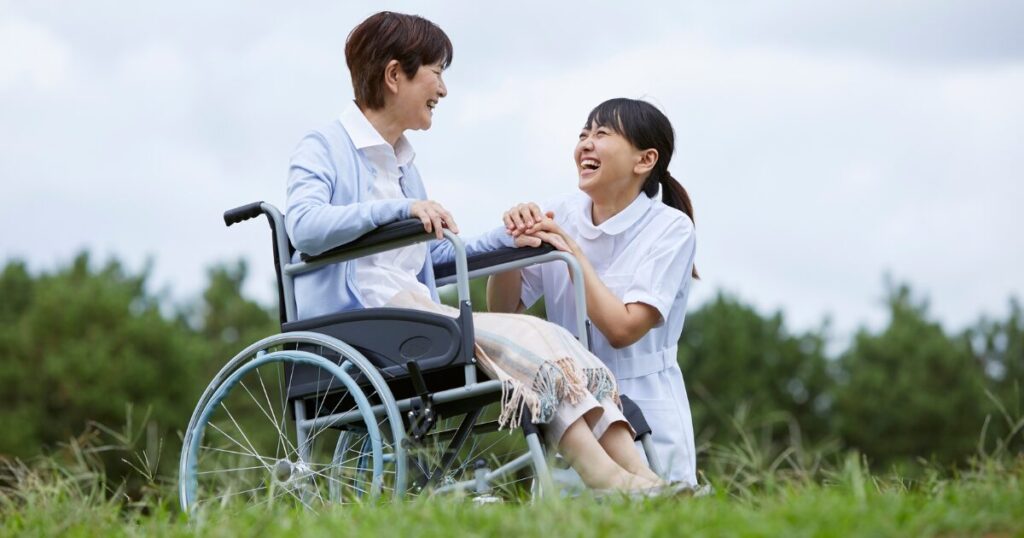 看護師が車椅子に乗った女性と笑顔で話している
