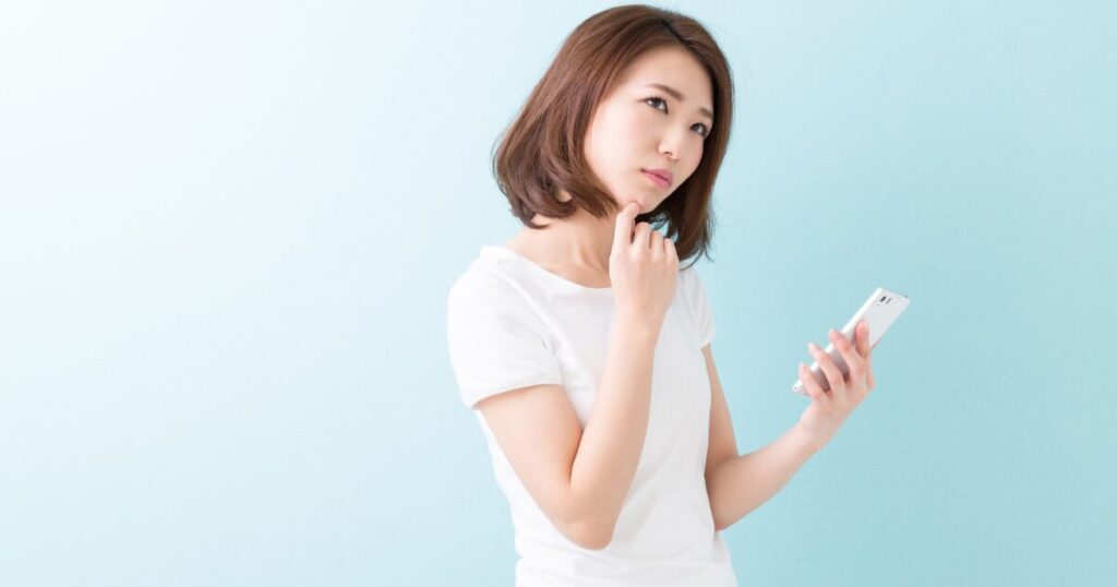 スマホを持って、悩んでいる女性