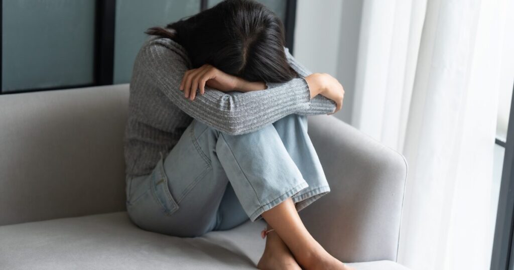 不安でうずくまっている女性